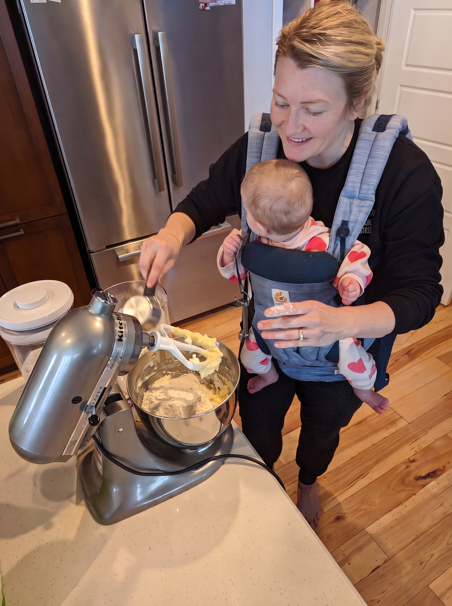 Throwback photo of Bre baking cookies with her baby in a carrier
